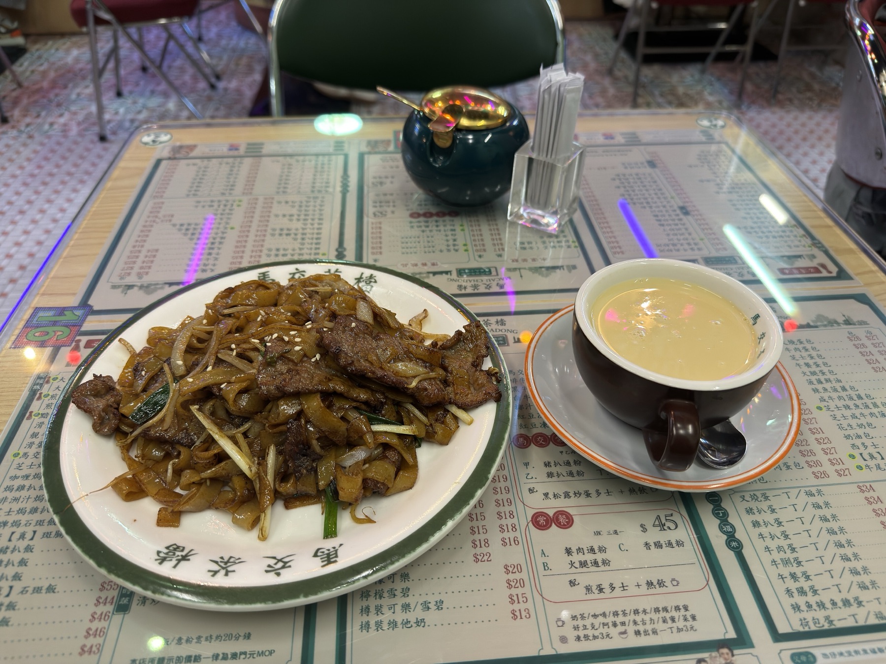 Beef chow fun and a cup of Hong Kong style milk tea on a cha chaan teng table